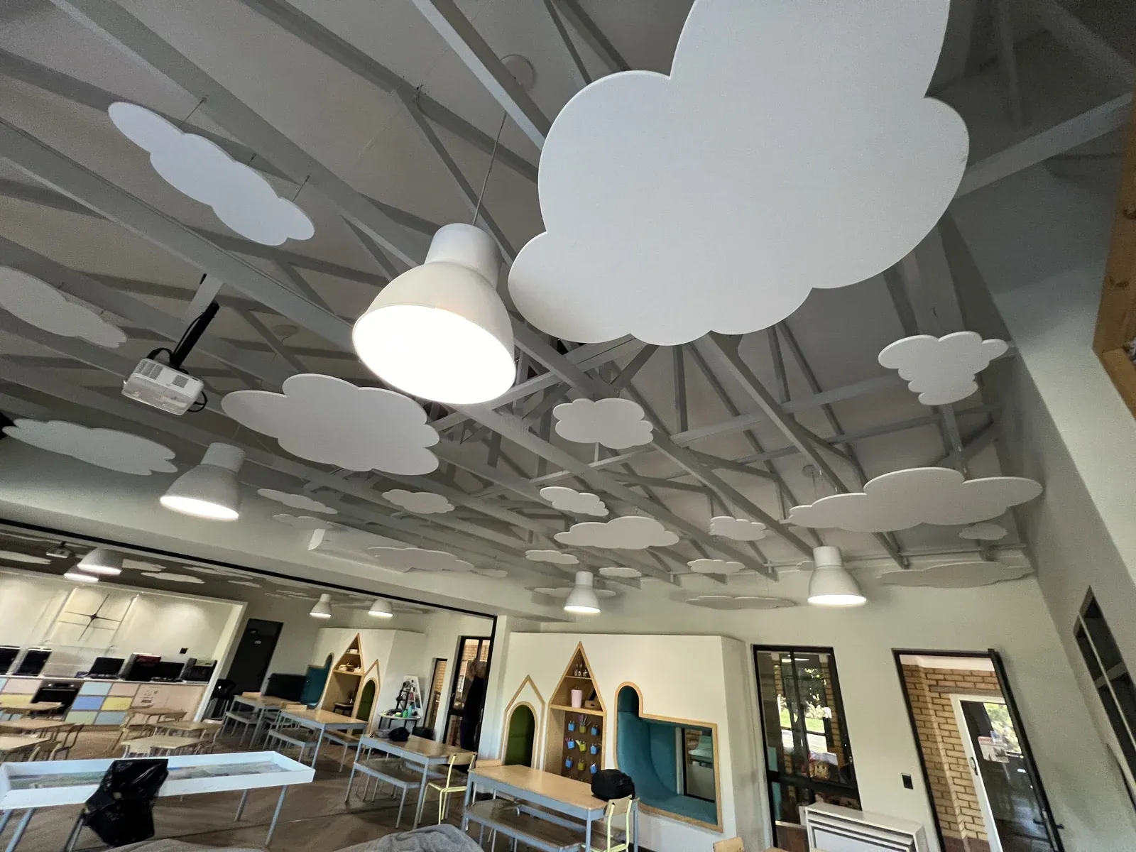 White felt clouds of different sizes hung between pendant lights above a Johannesburg classroom