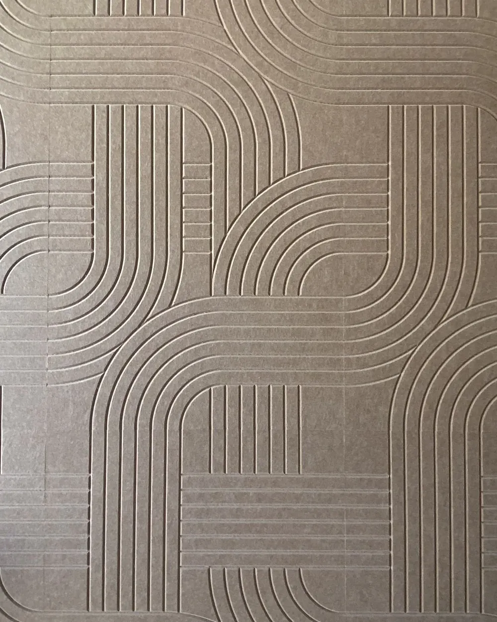 Close-up of taupe felt panels with curved, parallel grooves cut into the surface