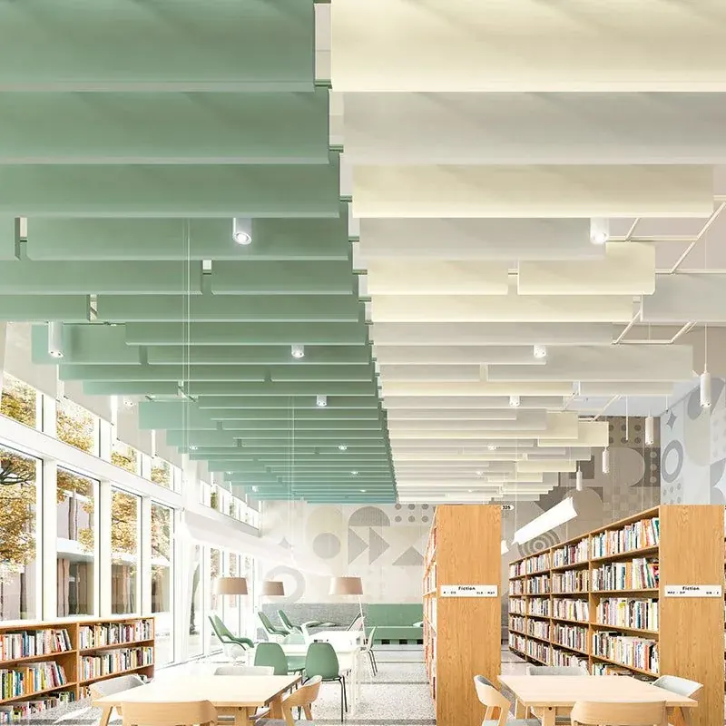 Green acoustic baffles hanging above a library with bookshelves and tables