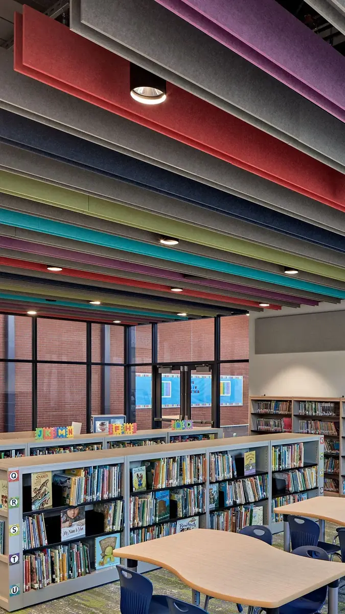 Rows of acoustic baffles in bright colours above library shelves