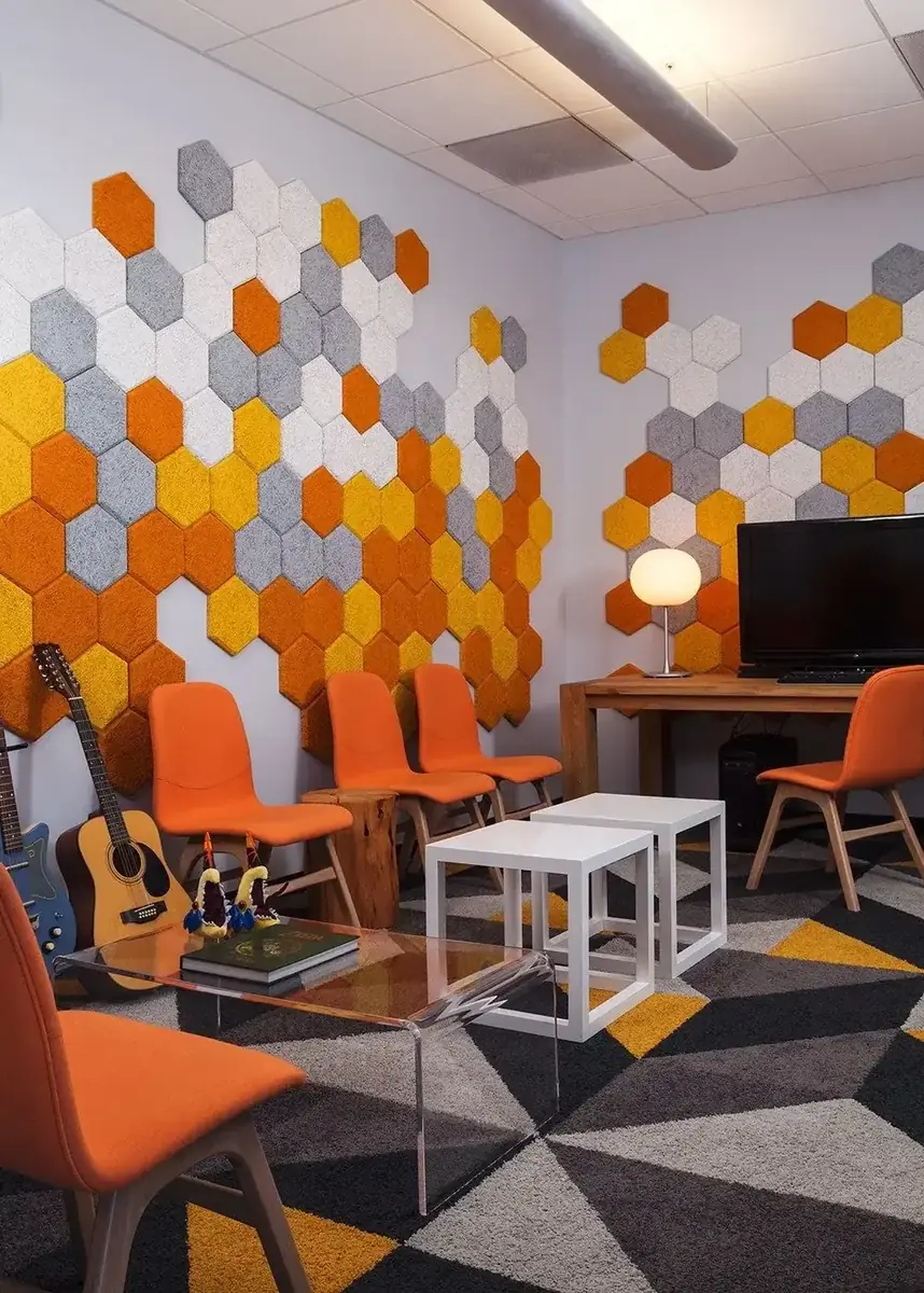 Orange, yellow and grey hexagon acoustic panels on a lounge wall
