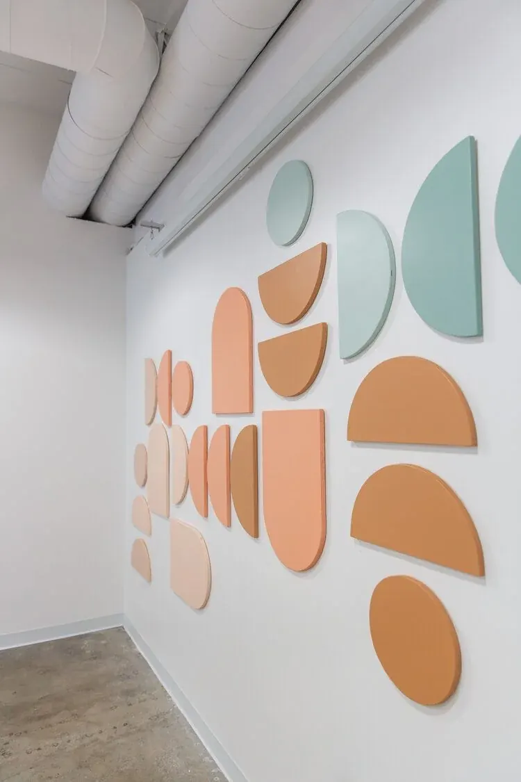 Peach and mint felt shapes arranged on a white wall